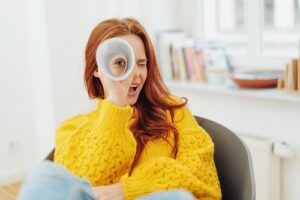 Frau schaut durch ein Fernrohr aus Papier in die Kamera.